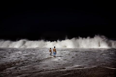 Due ragazzi attendono l’infrangersi di una grande onda contro la spiaggia dell’Arpoador. Rio de Janeiro, Brasile. Maggio 2008